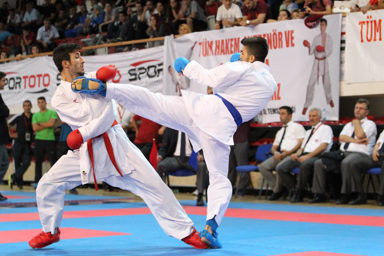 Two athletes in a karate match, one landing a high kick