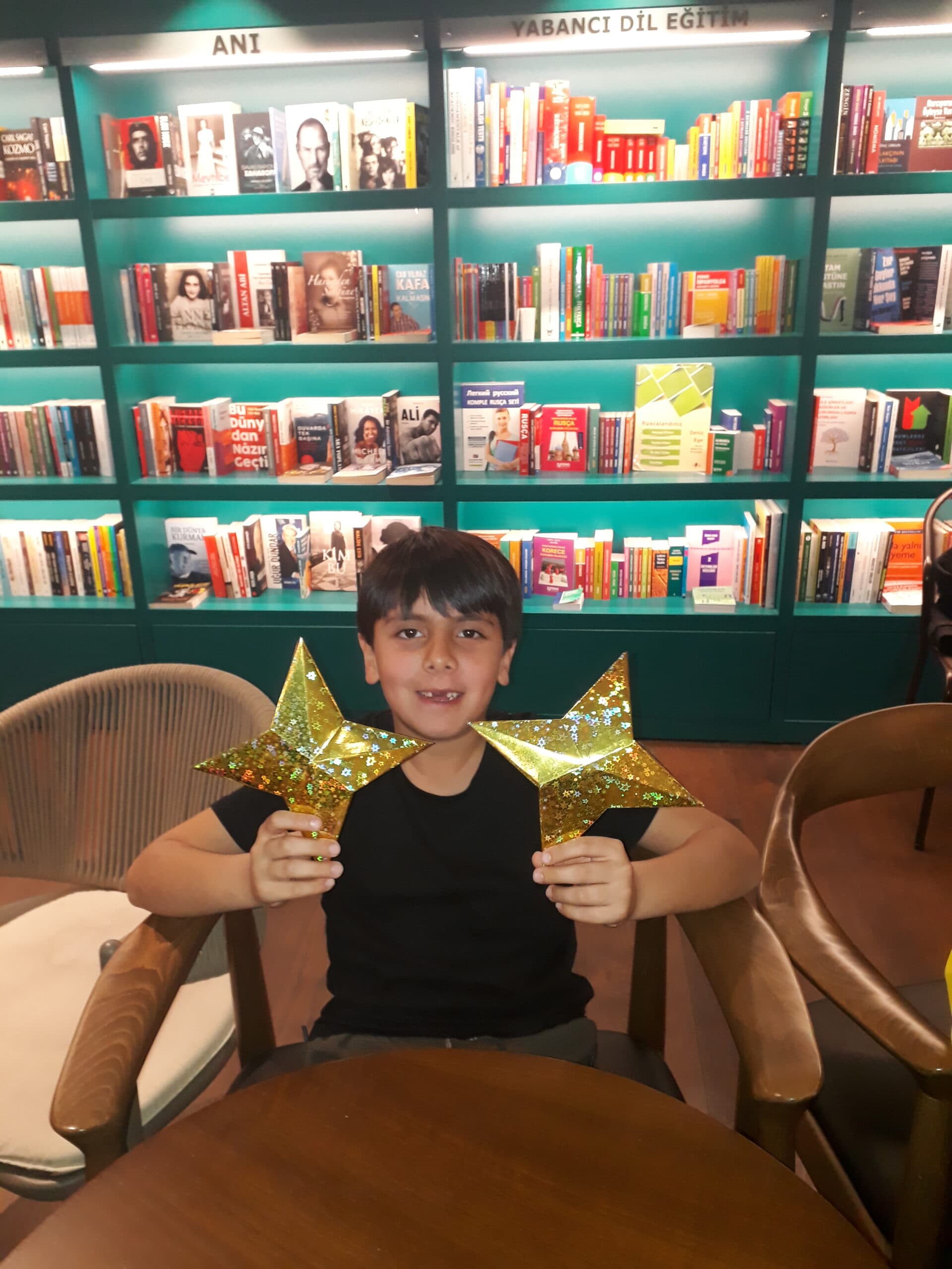 Child holding two gold origami stars at the origami event in Robin Bookstore