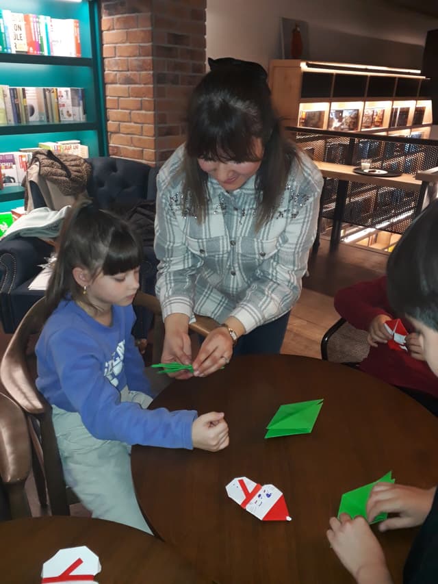 Participant folding paper with children at the origami event at Robin Bookstore