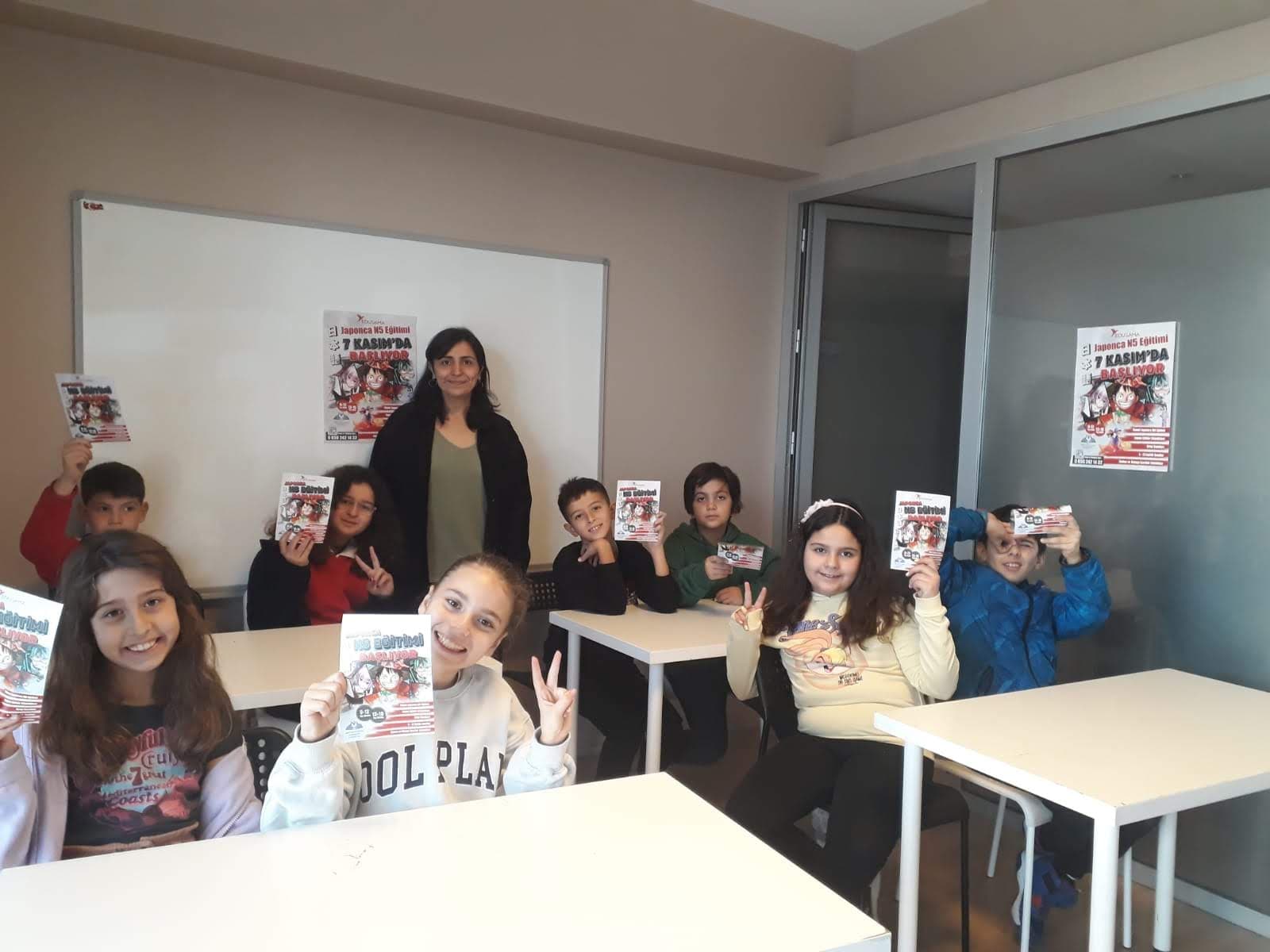 Children showing Japanese N5 course flyers in a classroom with their teacher