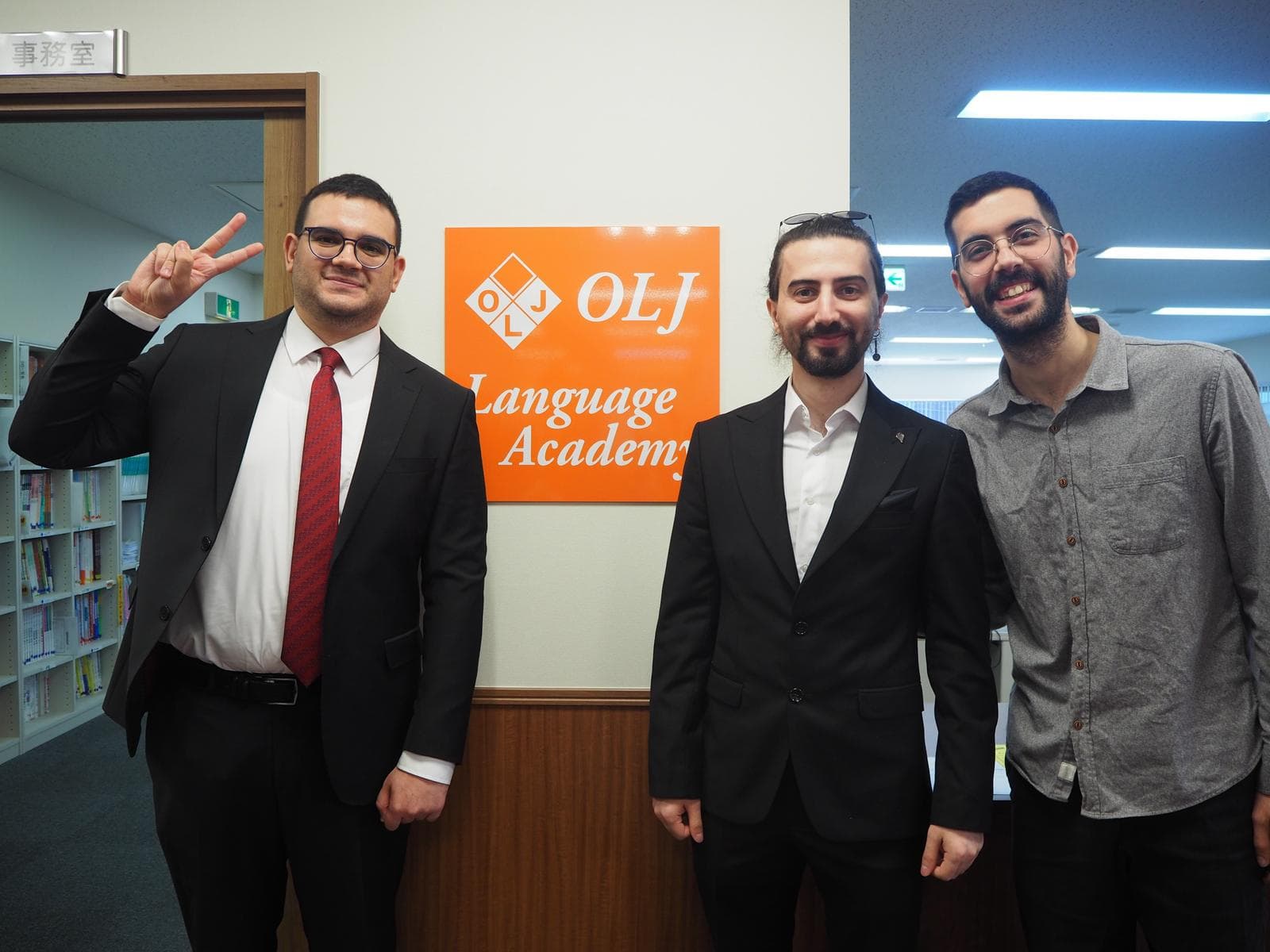 Three students posing next to the OLJ Language Academy sign in Tokyo
