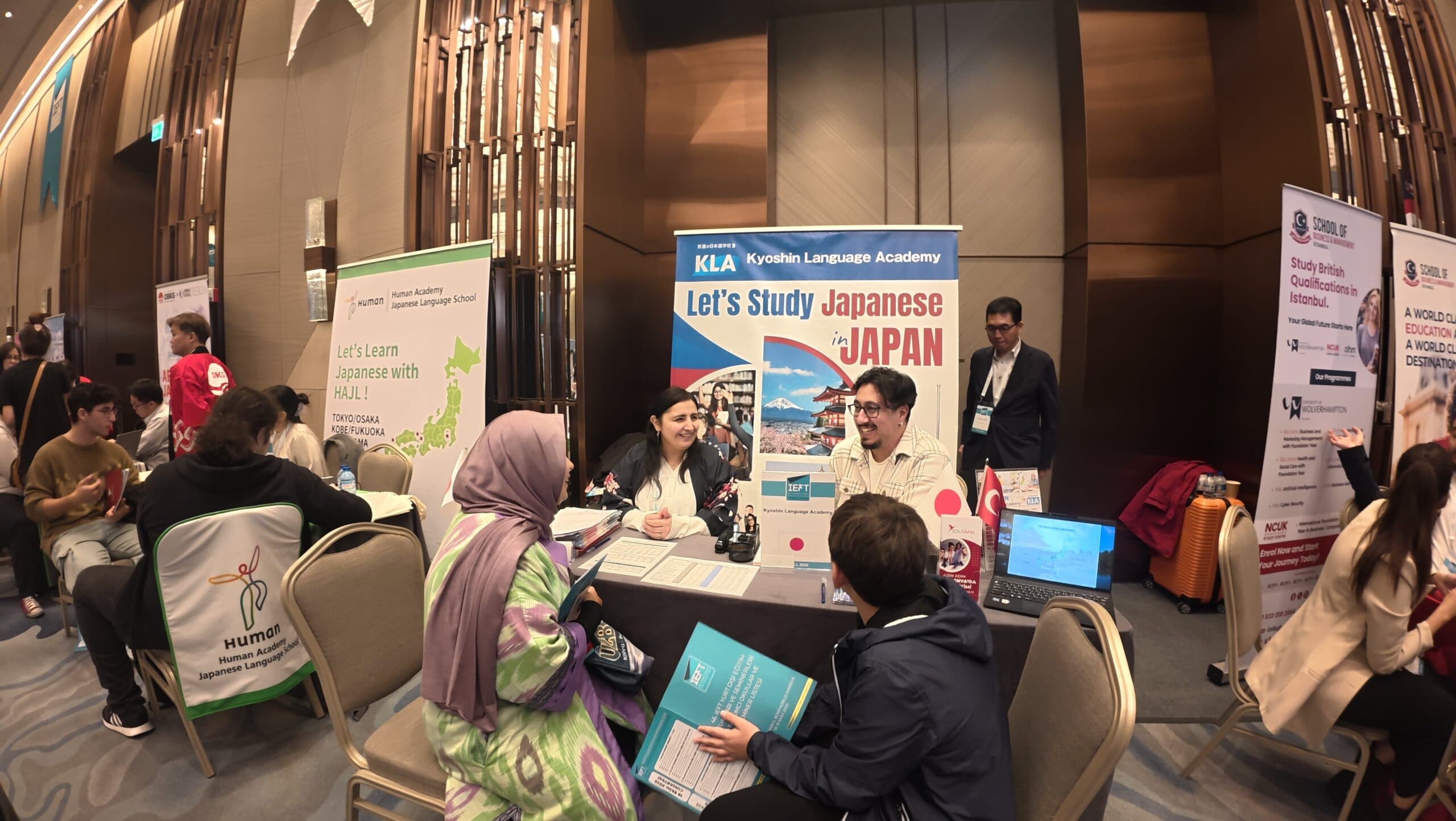 Advisers talking with students at the Kyoshin Language Academy booth at the IEFT fair
